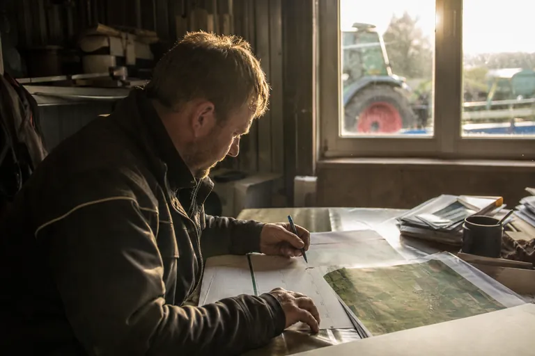 Landwirt trägt Düngetermine in einen Kalender neben einer Schlagkarte ein